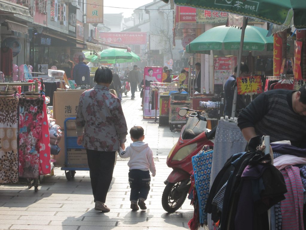 Older and younger person walking in market area